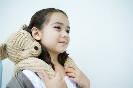 Little girl holding teddy bear on shoulders, smiling, looking away Stock Photo - Premium Royalty-Free, Code: 695-03389769