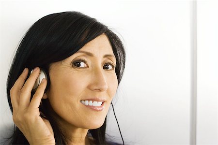simsearch:632-02745314,k - Woman listening to headphones, hand over ear, smiling at camera Foto de stock - Sin royalties Premium, Código: 695-03389795