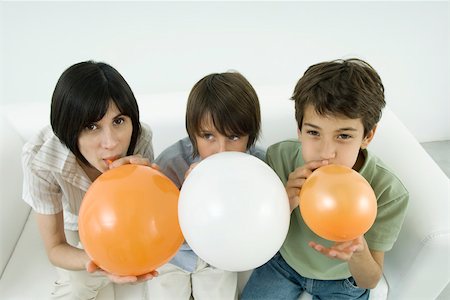 Mother and two sons inflating balloons, woman and one son looking at camera Stock Photo - Premium Royalty-Free, Code: 695-03389827