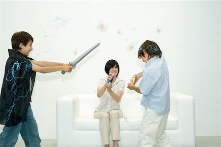 Mother and two sons playing with spray string, one boy holding toy sword Stock Photo - Premium Royalty-Free, Code: 695-03389833