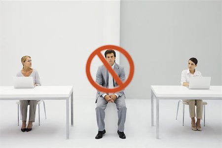 Deux femmes assises devant des ordinateurs portables, avertissement signe sur homme fronce les sourcils entre eux Photographie de stock - Premium Libres de Droits, Code: 695-03389933