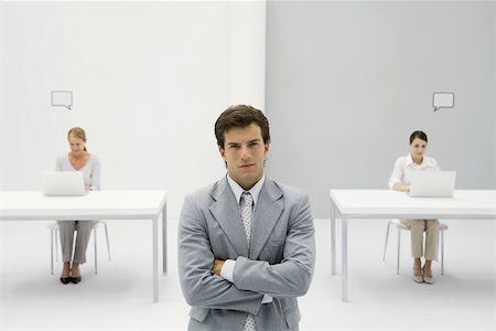 employee top view - Businessman standing with arms crossed, smirking at camera, women working in background Stock Photo - Premium Royalty-Free, Code: 695-03389945