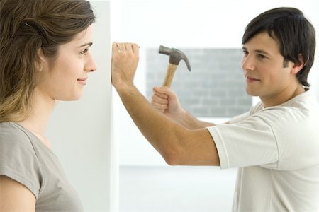 simsearch:695-03389240,k - Couple smiling at each other, man hammering nail into wall Stock Photo - Premium Royalty-Free, Code: 695-03389967