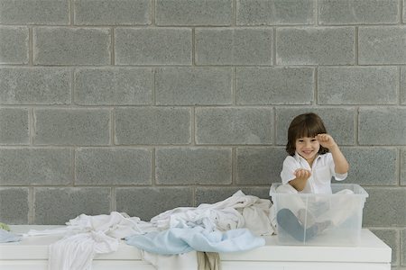 simsearch:695-03379065,k - Little boy sitting in plastic storage container, laundry strewn beside him, pretending to drive Foto de stock - Royalty Free Premium, Número: 695-03389969