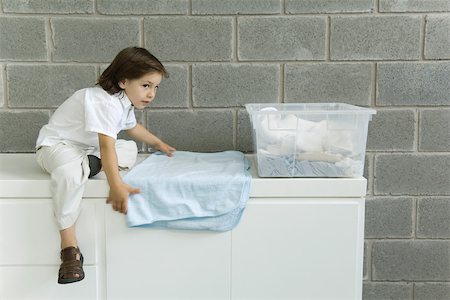 simsearch:695-03379065,k - Little boy folding laundry, sitting on counter Foto de stock - Royalty Free Premium, Número: 695-03389974