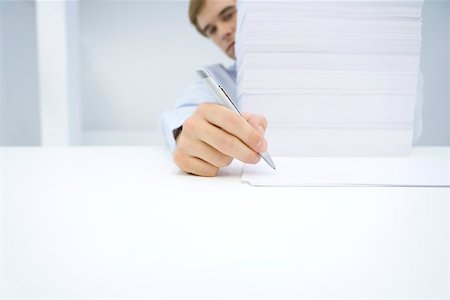 Homme assis derrière une grande pile de documents, écrit sur une seule feuille de papier Photographie de stock - Premium Libres de Droits, Code: 695-03380047