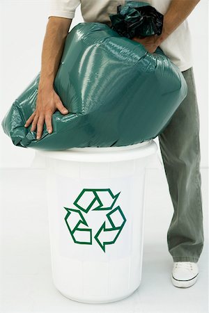 rubbish bag - Man forcing large garbage bag into recycling bin, cropped view Stock Photo - Premium Royalty-Free, Code: 695-03380098