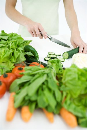 Woman slicing cucumber, assorted vegetables in foreground, cropped view Stock Photo - Premium Royalty-Free, Code: 695-03380102