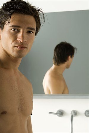 Bare-chested man looking at camera, mirror in background Stock Photo - Premium Royalty-Free, Code: 695-03380115