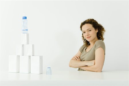 pyramid people - Woman beside stacked milk cartons and baby bottle, arms folded, smiling at camera Stock Photo - Premium Royalty-Free, Code: 695-03380146