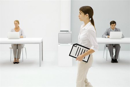 simsearch:695-05779472,k - Female office worker carrying document under arm, colleagues working in background Stock Photo - Premium Royalty-Free, Code: 695-03380191