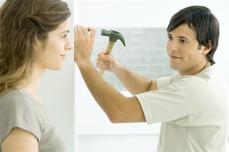 simsearch:695-03389240,k - Couple smiling at each other, man hammering nail into wall Stock Photo - Premium Royalty-Free, Code: 695-03380210