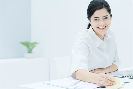 simsearch:695-03380090,k - Young woman fidgeting with adhesive notes, smiling at camera Stock Photo - Premium Royalty-Free, Code: 695-03380263