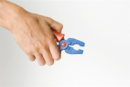futility - Hand holding toy pliers, cropped view Foto de stock - Sin royalties Premium, Código: 695-03380275