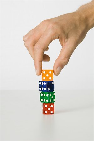 dice game picture - Hand stacking colorful dice, cropped view Stock Photo - Premium Royalty-Free, Code: 695-03380277