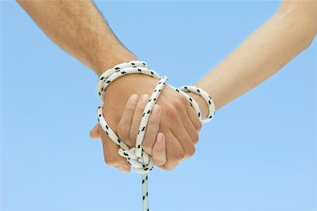 Man and woman holding hands, tied together with rope, cropped view Foto de stock - Royalty Free Premium, Número: 695-03380288