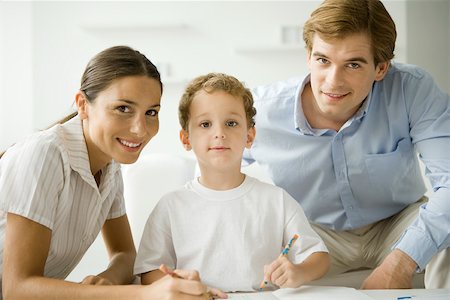 Little boy sitting with parents, drawing with pencil, all smiling at camera Stock Photo - Premium Royalty-Free, Code: 695-03380334