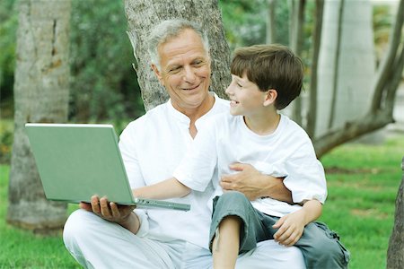 Grand-père holding petit-fils tour, garçon regardant ordinateur portable, les deux souriant Photographie de stock - Premium Libres de Droits, Code: 695-03380390