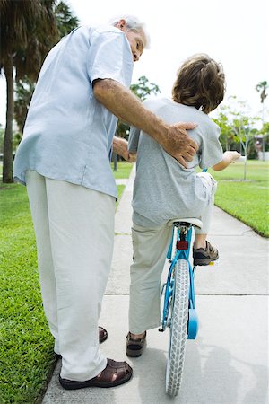 simsearch:633-03444677,k - Senior man helping his grandson learn to ride a bicycle Stock Photo - Premium Royalty-Free, Code: 695-03380419