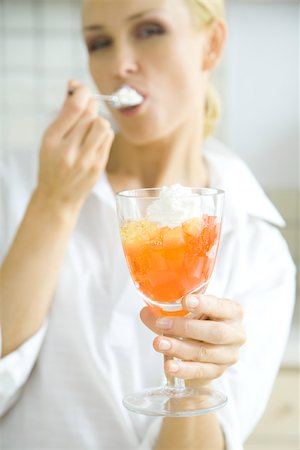 Woman eating jellied fruit dessert with whipped cream Stock Photo - Premium Royalty-Free, Code: 695-03380448