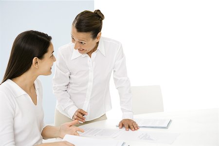 Two professional women discussing documents, smiling at each other Foto de stock - Sin royalties Premium, Código: 695-03380489