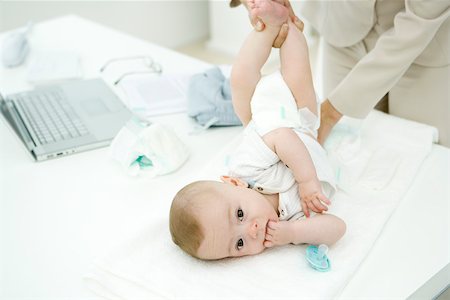 simsearch:632-05991180,k - Professional woman changing infant's diaper on desk, infant looking at camera Foto de stock - Sin royalties Premium, Código: 695-03380545