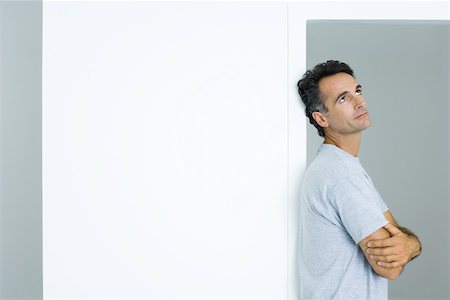 daydreamer man - Man leaning against doorway with arms folded looking up Stock Photo - Premium Royalty-Free, Code: 695-03380557