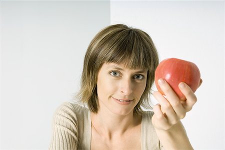 Woman holding red apple, smiling at camera Stock Photo - Premium Royalty-Free, Code: 695-03380583