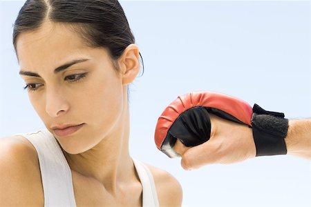Woman turning head away from hand in boxing glove, close-up Stock Photo - Premium Royalty-Free, Code: 695-03380597
