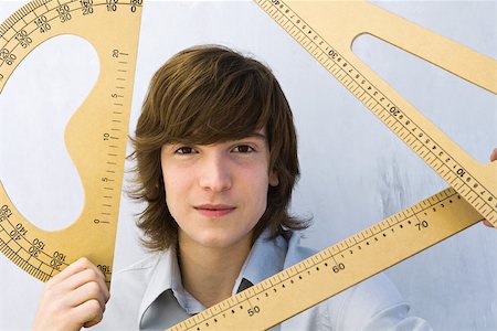 Young man holding various measuring instruments, smiling at camera Stock Photo - Premium Royalty-Free, Code: 695-03380602