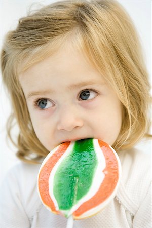 Toddler girl eating large lollipop, looking away Foto de stock - Sin royalties Premium, Código: 695-03380610