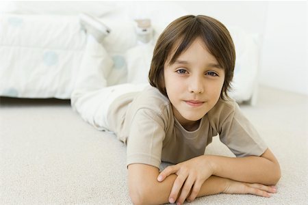 Boy lying on the floor in bedroom, smiling at camera Stock Photo - Premium Royalty-Free, Code: 695-03380620