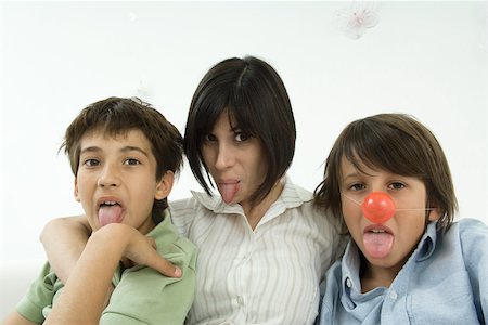 Mother and two sons sticking out tongues, one boy wearing clown's nose Fotografie stock - Premium Royalty-Free, Codice: 695-03380679