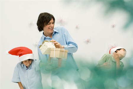 simsearch:632-02690128,k - Young man with presents, playing with two boys wearing Santa hats Stock Photo - Premium Royalty-Free, Code: 695-03380672