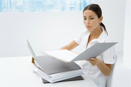 simsearch:695-05767911,k - Woman sitting at desk, looking at stacked binders Stock Photo - Premium Royalty-Free, Code: 695-03380717