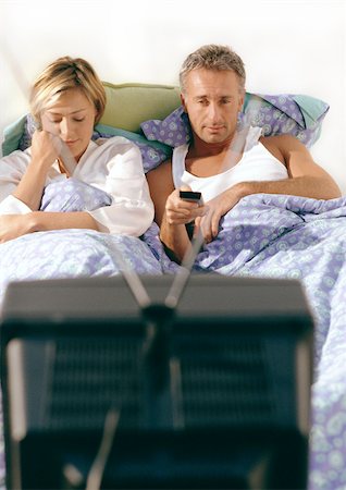 Couple lying in bed watching television. Stock Photo - Premium Royalty-Free, Code: 695-03380979