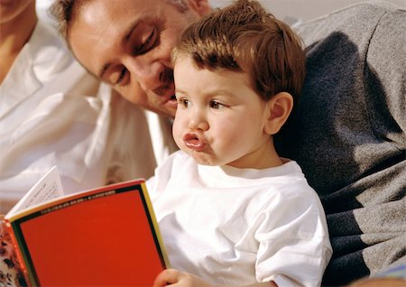 Young child making goofy face, looking at book with older man. Stock Photo - Premium Royalty-Free, Code: 695-03380988