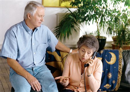 elderly couple concern - Man sitting next to woman on phone inside. Stock Photo - Premium Royalty-Free, Code: 695-03380983