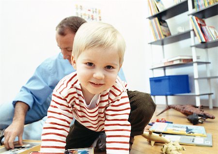 person on all four - Young child facing camera in room with father Stock Photo - Premium Royalty-Free, Code: 695-03381008