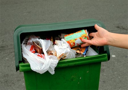 dirty city - Person putting aluminum can into overflowing trash bin Stock Photo - Premium Royalty-Free, Code: 695-03381104