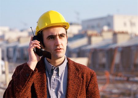 phone in front of face - Man wearing hard hat, using cell phone Stock Photo - Premium Royalty-Free, Code: 695-03381121