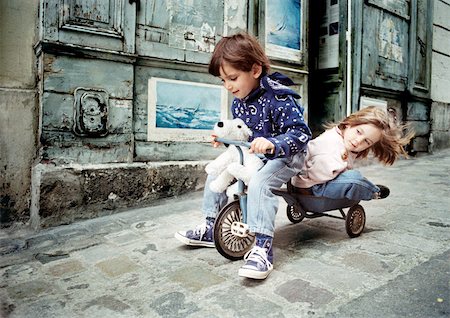 Little boy riding tricycle with little girl on back Stock Photo - Premium Royalty-Free, Code: 695-03381140