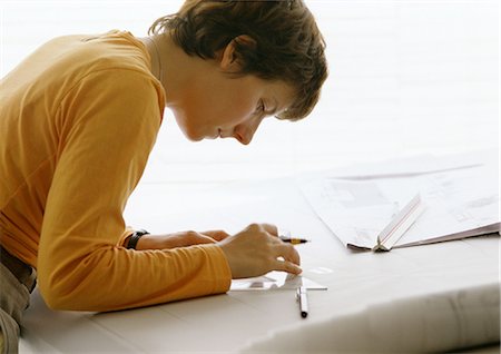 engineer drafting - Woman bending over table, holding set square and pen, side view Stock Photo - Premium Royalty-Free, Code: 695-03381192