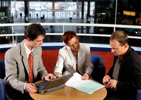 simsearch:632-03779792,k - Three people sitting at table, one holding laptop computer Stock Photo - Premium Royalty-Free, Code: 695-03381210