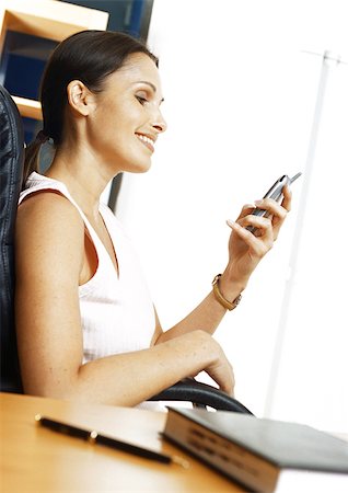 simsearch:632-02745019,k - Woman sitting in armchair, looking at cell phone, side view Stock Photo - Premium Royalty-Free, Code: 695-03381246