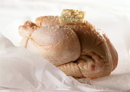 Whole raw chicken and with pat of butter on top, on cooking paper, close-up Stock Photo - Premium Royalty-Free, Code: 695-03381289