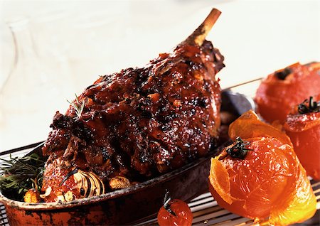 Roasted leg of lamb with tomatoes and herbs, in casserole dish, close-up Stock Photo - Premium Royalty-Free, Code: 695-03381307