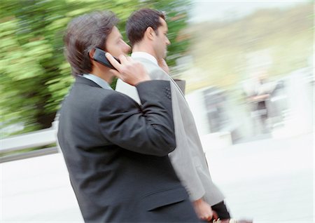 simsearch:696-03402965,k - Two businessmen walking outside, using cell phones, side view Stock Photo - Premium Royalty-Free, Code: 695-03381586