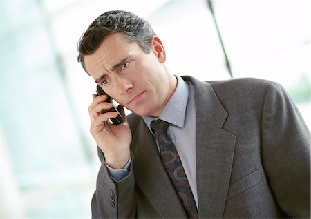 Businessman using cell phone, furrowing brow, portrait Stock Photo - Premium Royalty-Free, Code: 695-03381591