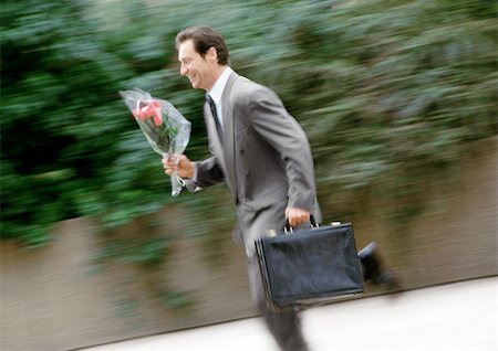 date (time) - Businessman holding briefcase and bouquet of flowers, running, blurred Stock Photo - Premium Royalty-Free, Code: 695-03381626